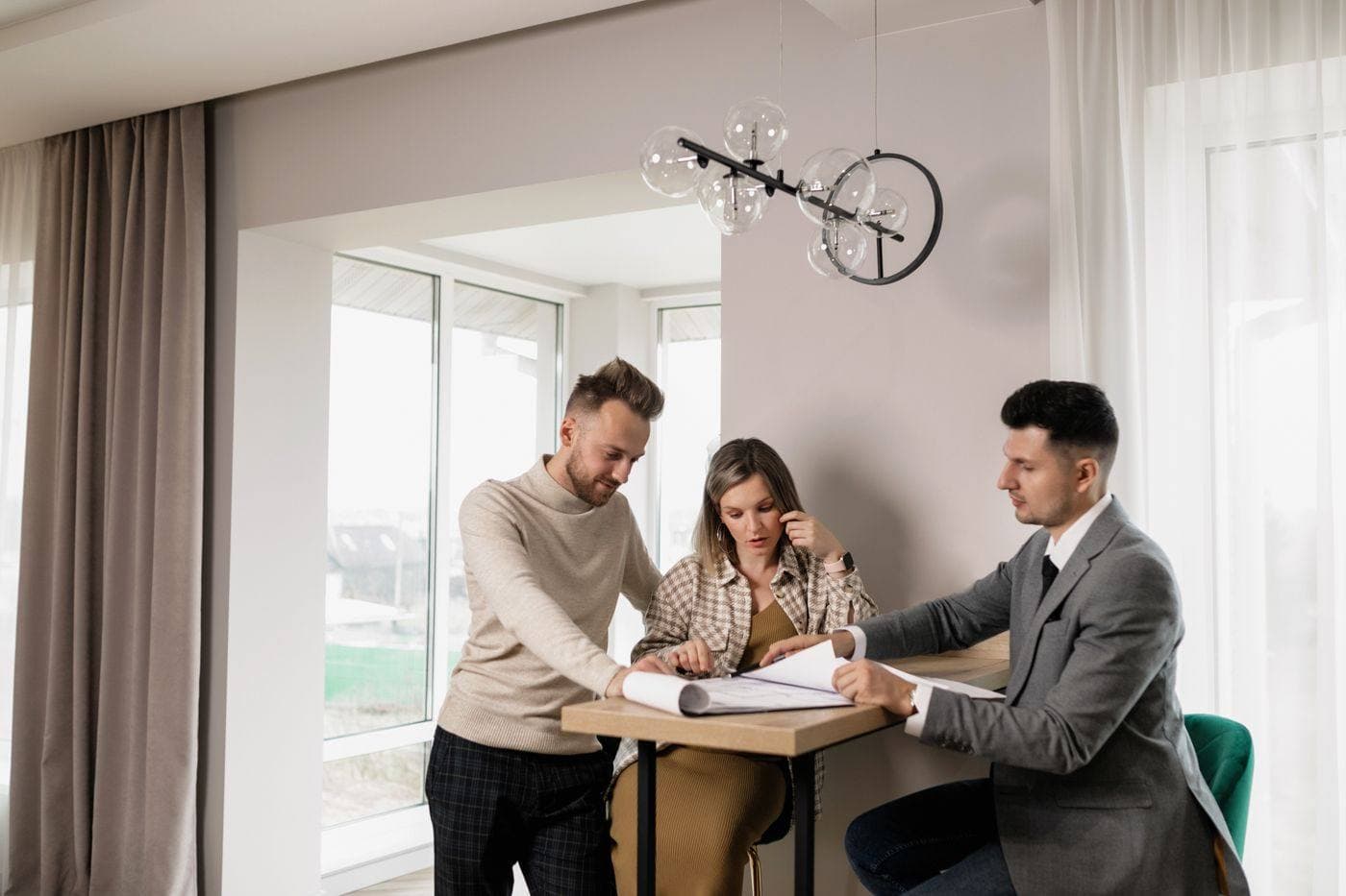 Two people reviewing paperwork at a table with a third person