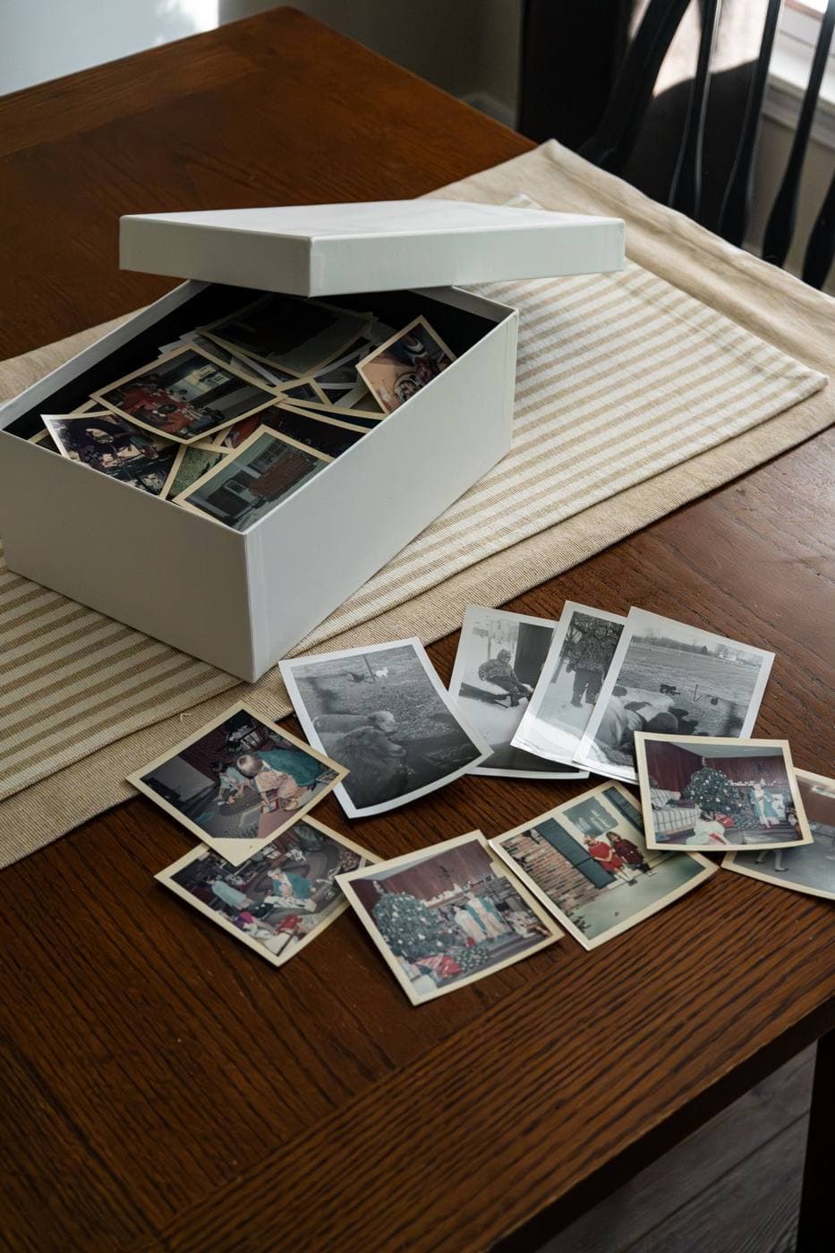 A box and loose family photographs on a wooden table