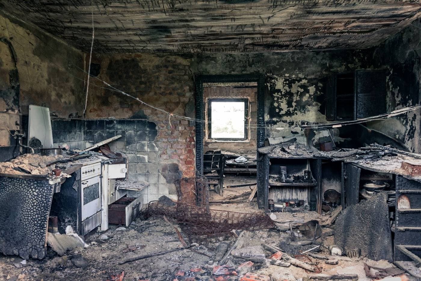 Kitchen blackened by fire with debris on the floor