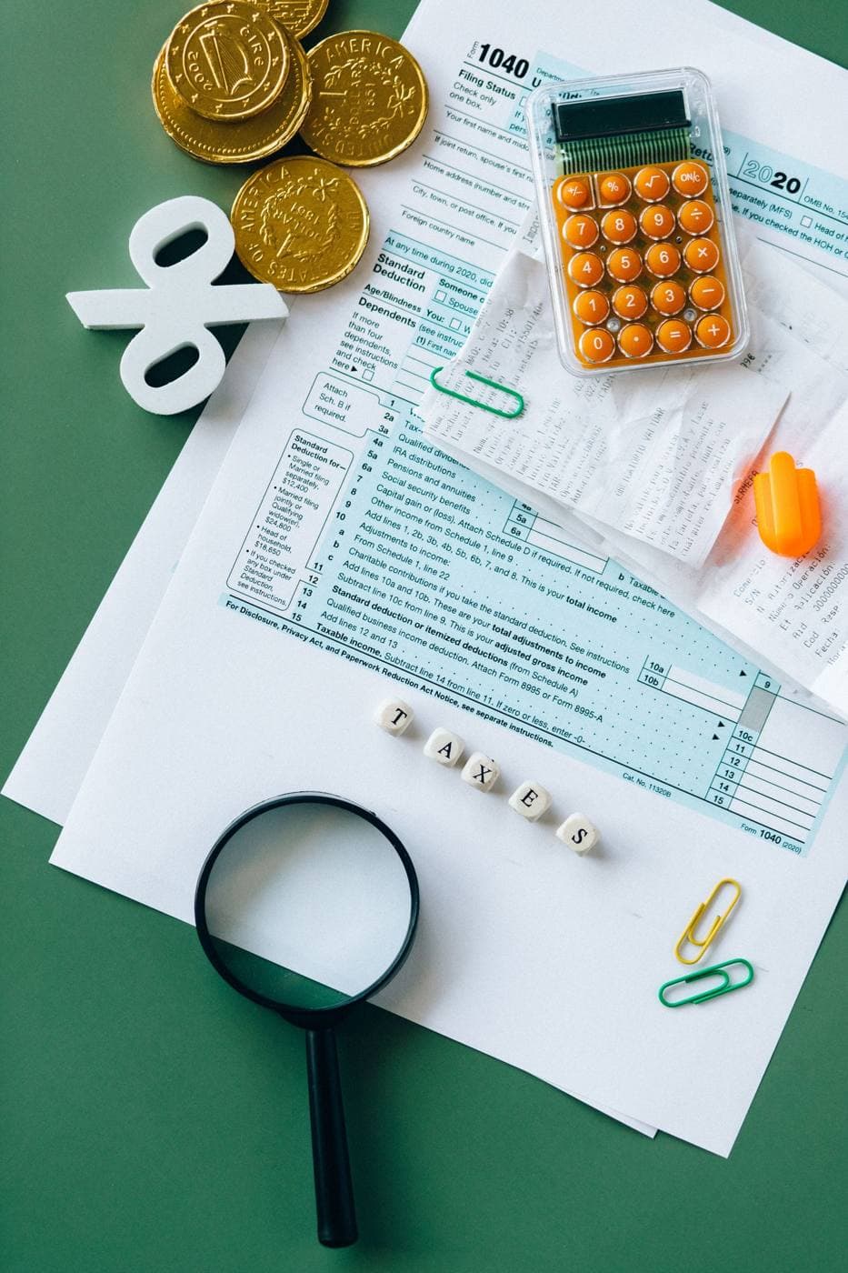 A calculator, coins and tax forms laid out on a desk