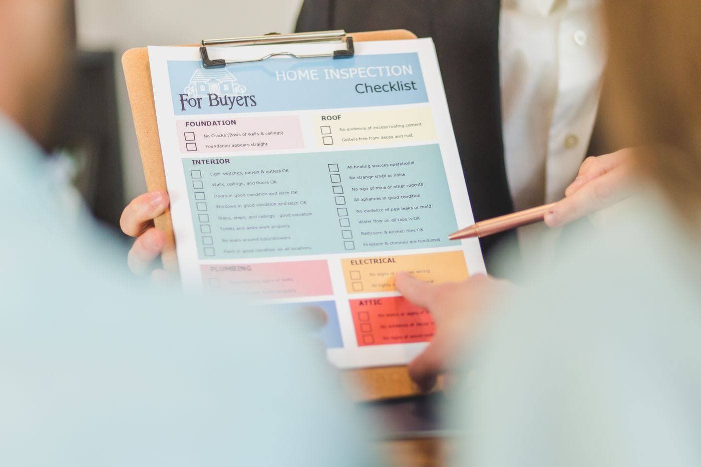Hands holding a home inspection checklist on a clipboard