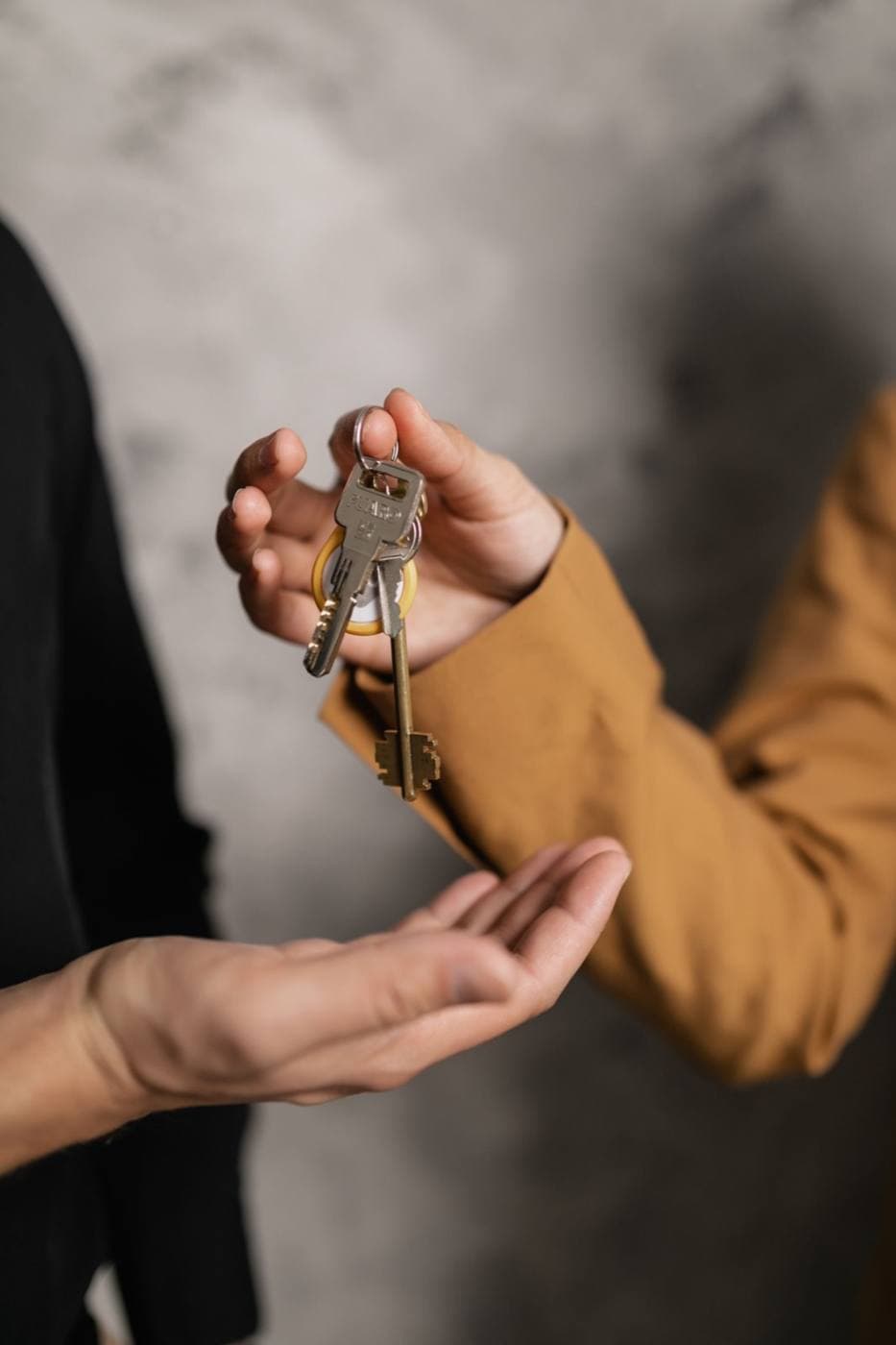 One person handing a set of house keys to another