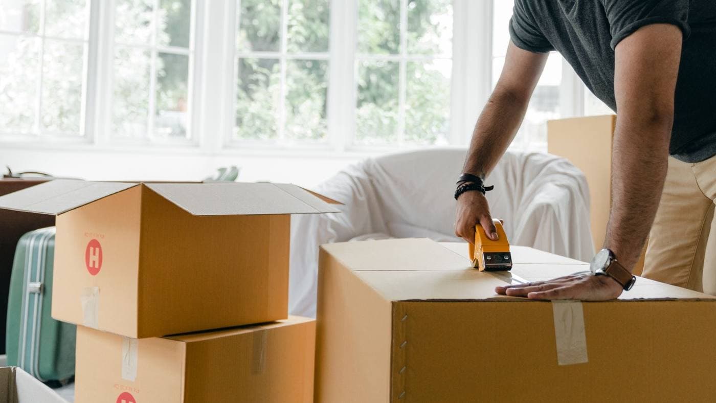 Person sealing a moving box with packing tape